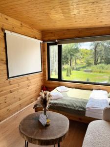 ein Zimmer mit einem Bett und einem Tisch und einem großen Fenster in der Unterkunft глемпінг Обійми in Yatski