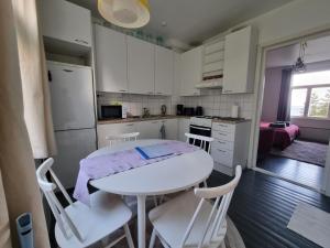 una pequeña cocina con mesa blanca y sillas en Pispalan Helmi - Koti Näköalalla, en Tampere