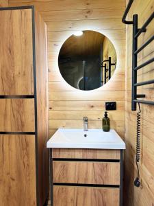 ein Badezimmer mit Waschbecken und Spiegel in der Unterkunft глемпінг Обійми in Yatski