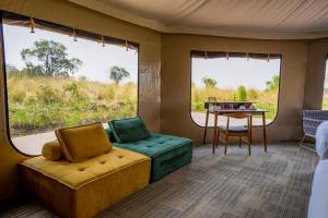 a room with a couch and a table and windows at Malaika Ndutu Luxury Camp in Sinoni