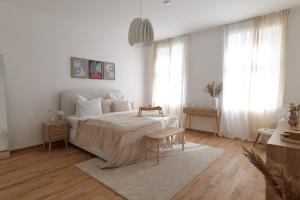 a white bedroom with a large bed and a table at Apartment Grace Family in Vienna