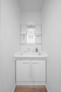 a white bathroom with a sink and a mirror at Furano Resort Wakaba D in Furano