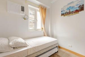 a bed in a white room with a window at 2BR FULLY FURNISHED Trees Residences Near SM Fairview with NETFLIX AND KARAOKE in Manila