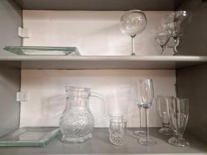 four wine glasses and a vase on a shelf at Lakeview terrace studio in Namulanda