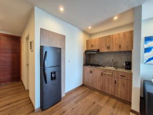 a kitchen with a refrigerator and wooden cabinets at Moderna suite con balcón a pasos de la playa in Cartagena de Indias