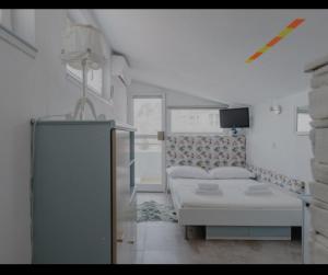 a white room with a bed and a tv at Brela SP small loft-no parking in Brela