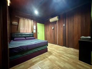 a bedroom with a bed and wooden walls and wooden floors at AISHAH GUEST HOUSE in Perhentian Islands +3 photos