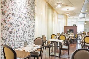 a restaurant with tables and chairs and a floral wall at Logis Grand H&ocirc;tel Des Bains in Salins-les-Bains