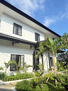a white house with palm trees in front of it at White Swan Mansion in Ketewel
