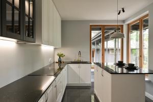 een keuken met witte kasten en zwarte aanrechtbladen bij Villa VILAVI Jurmala in Jūrmala
