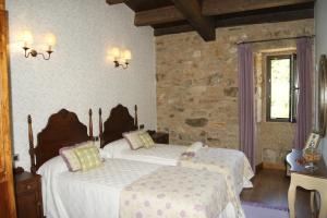 a bedroom with two beds and a stone wall at A Eira da Laxe in Cerdedo