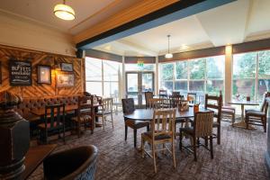 a dining room with tables and chairs and windows at Brentwood Inn by Greene King Inns in Rotherham