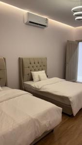 Dos camas sentadas en una habitación con un televisor. en شقة أنيقة دخول ذاتي, en Hail