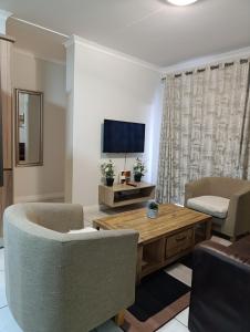 a living room with two chairs and a table and a television at Luxury Apartment at The Blyde Crystal Lagoon in Pretoria +6 photos