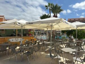 an outdoor cafe with tables and chairs and umbrellas at Wonderful stay in Tenerife Royal Gardens Resort! in Playa de las Americas