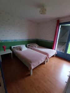a bedroom with two beds and a window at Villa Les hortensias RDC in Maniquerville