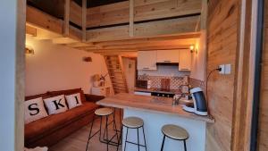 eine Küche mit einer Theke und Stühlen in einem winzigen Haus in der Unterkunft Cocon au cœur des Montagnes in Puyvalador