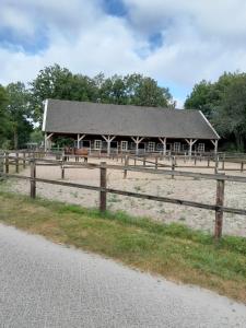 a barn with a wooden fence in front of it at 6 persoons stacaravan Drenthe in Hoogersmilde