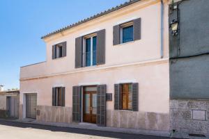 a pink building with black shuttered windows at Bouganvilla House in Ariany
