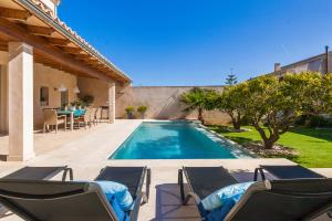 a swimming pool with chairs and a table on a patio at Bouganvilla House in Ariany