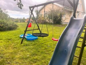 a playground with a swing in a yard at Spacious Villa In The Countryside Near The Beach in Fakse Ladeplads