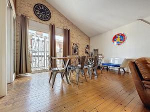 una sala da pranzo con tavolo, sedie e orologio sul muro di Superbe LOFT centre-ville - Sauna - parking privé -Clim- 1 à 10personnes a Brive-la-Gaillarde