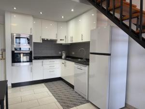 a kitchen with white cabinets and a staircase at Stunning sea view Tenerife Royal Gardens Resort! in Playa de las Americas
