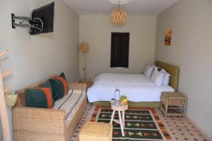 a bedroom with a bed and a couch and a tv at La PERLE DE OUIRGANE in Ouirgane