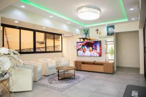 a waiting room with white chairs and a flat screen tv at Ethan Palace in Kofa