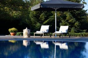 twee stoelen en een parasol naast een zwembad bij Escape Villa in Melissochori in Melissochórion