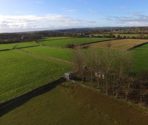 an aerial view of a green field with a fence at Secluded off grid Shepherd's Hut in Minchinhampton