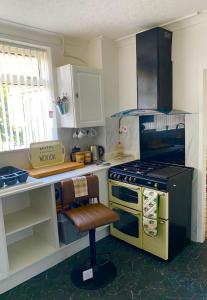 a kitchen with a stove and a chair in it at Northern homestay between High Peak & Manchester in Hadfield +9 photos