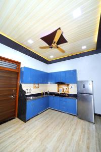 cocina con armarios azules y ventilador de techo en The Taj Wings Home Stay, en Agra