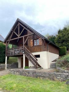 une grande maison en bois avec un porche et des escaliers dans l'établissement Chalet 6 personnes Besse et Saint Anastaise, à Besse-et-Saint-Anastaise