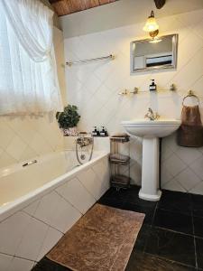 a bathroom with a sink and a bath tub and a sink at Bergvliet Cottages - Salvado and Esparanza in Clarens