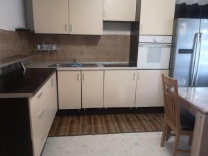 a kitchen with white cabinets and a table and a refrigerator at Evergreen in Banja Luka
