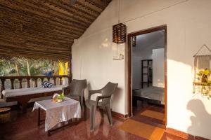 a room with a bed and a table and chairs at Forget Me Not Resort in Agonda