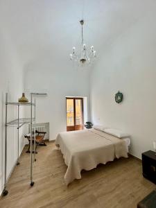 a white bedroom with a bed and a chandelier at Dimora Donna Carmela in Capaci