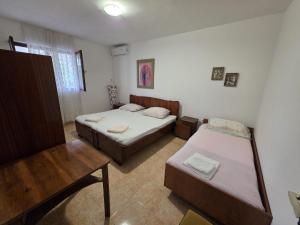 a room with two beds and a table in it at Apartman Antica in Komiža