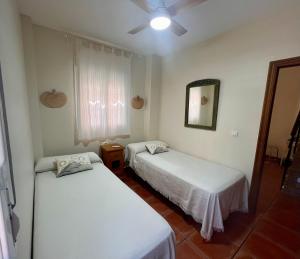 1 Schlafzimmer mit 2 Betten, einem Spiegel und einem Fenster in der Unterkunft Casa Verdemar Golf Islantilla in Islantilla + 10 Fotos