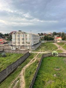 a building on a hill with a field and buildings at Treands Apartments in Nakuru