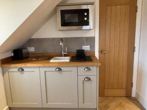 a kitchen with a sink and a tv on the wall at Tranquil Tenterden Apartment Retreat in Tenterden +8 photos