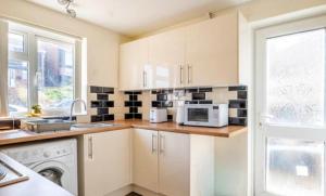 a kitchen with white cabinets and a microwave at Elegent Devon Retreat in Luton in Luton +5 photos