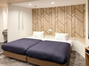 a bedroom with a large bed with a blue blanket at Hotel LiVEMAX Naha Naminoue 1 in Naha