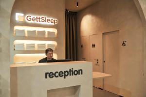 a man sitting at a reception desk with a laptop at GettSleep Madrid Airport T4S - Boarding Pass Required in Madrid