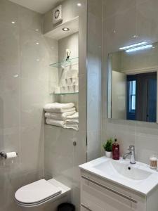 Un baño con lavabo, inodoro y espejo. en London Luxe Escape, en Londres