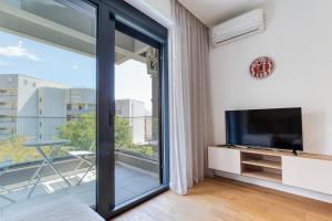 sala de estar con TV y puerta corredera de cristal en Aura Zafiro, en Budva