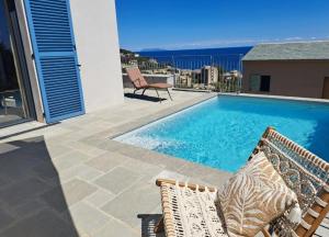 a swimming pool with two lounge chairs next to a building at Casa Lunga à Erbalunga- A deux pas de la plage in Brando