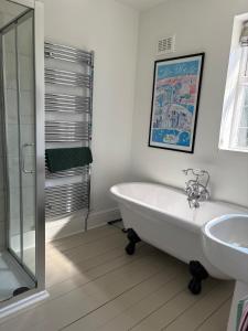 a white bathroom with a tub and a sink at Coastal Family Escape with Castle Views in Deganwy