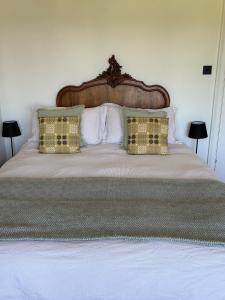 a large bed with a wooden headboard and pillows at Coastal Family Escape with Castle Views in Deganwy
